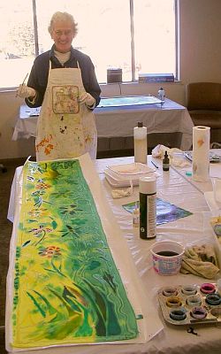 Woman painting large green and yellow silk scarf